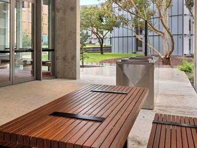 Wooden bench and modern trash cans outside La Trobe University - North and South Apartments.