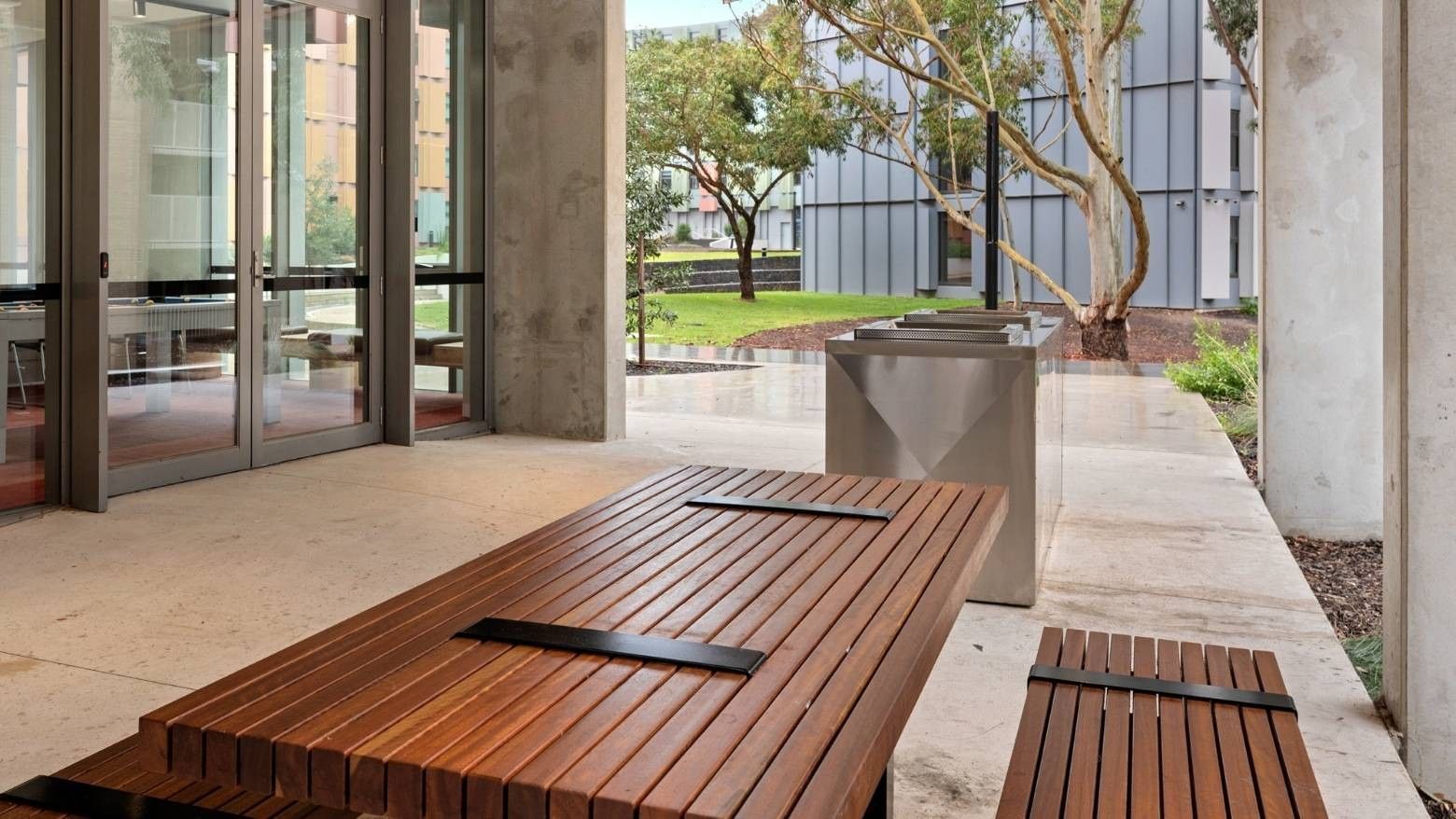 Wooden bench and modern trash cans outside La Trobe University - North and South Apartments.