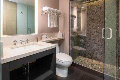 Bathroom interior featuring a white vanity placed by a shower with dark, textured stone tile at Hotel Keen 