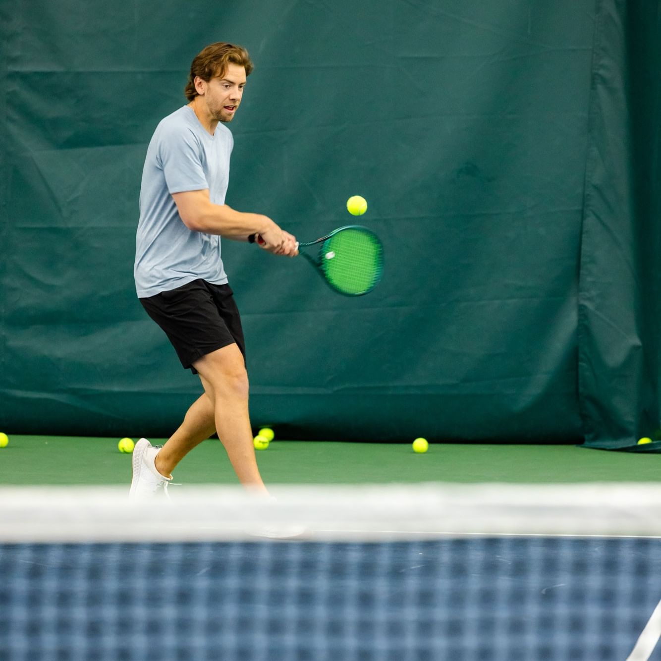 A man playing tennis with a racket on a court in a Men's 3.0+ Round Robin event.