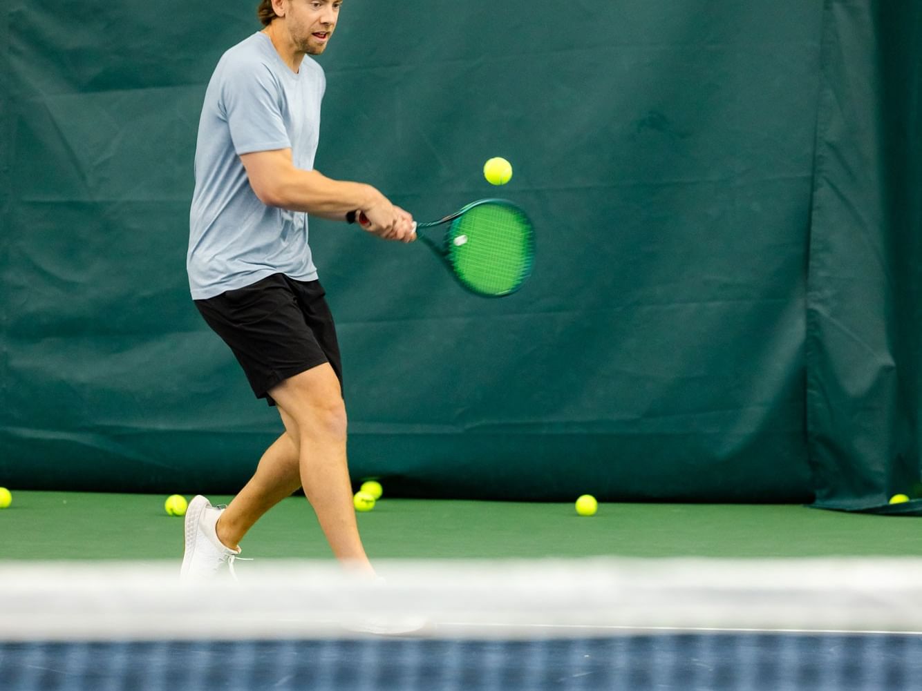 A man playing tennis with a racket on a court in a Men's 3.0+ Round Robin event.