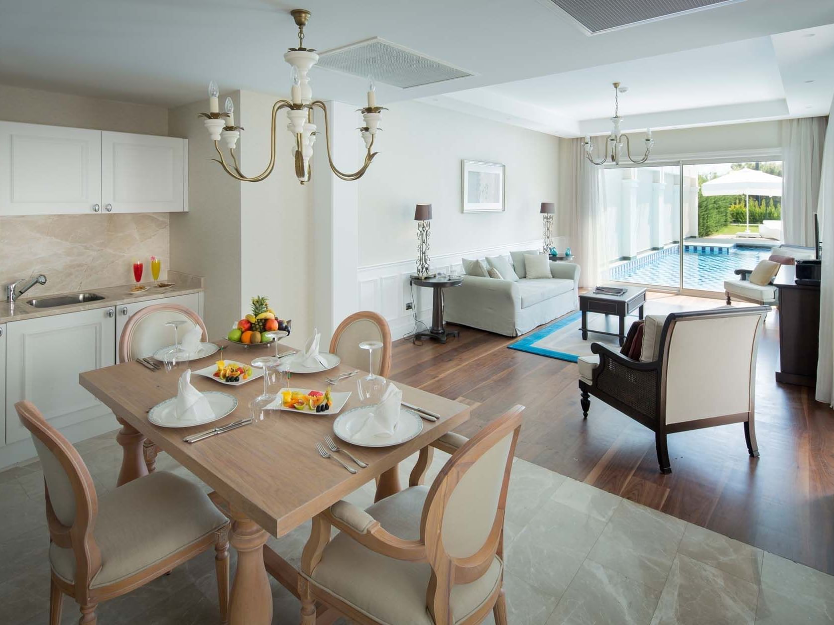 TV lounge area & kitchenette in Design Pool Villa with wooden floors at Titanic Deluxe Golf Belek