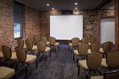 Theater-style chair set-up with projector screen in Savannah Meeting Spaces at River Street Inn