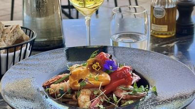 Plat de fruits de mer et légumes avec vin et huile d'olive sur une table en plein air.