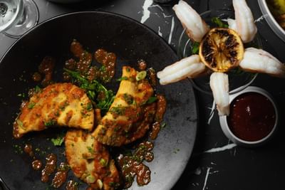 Grilled chicken and shrimp dish with sauce, garnished with a lemon slice on a plate at The Delegate Hotel