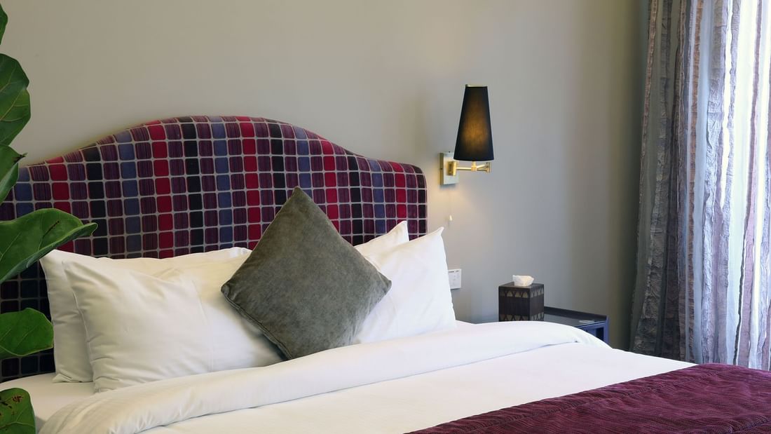 King bed with a cushioned headboard and side table in Senior Suite Bed at Warwick Palm Beach Hotel