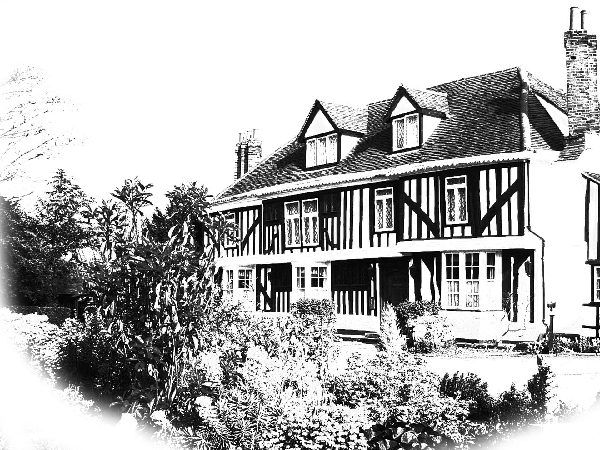 Stylish black-and-white exterior of Marygreen Manor, showcasing Tudor-style architecture and neatly manicured gardens