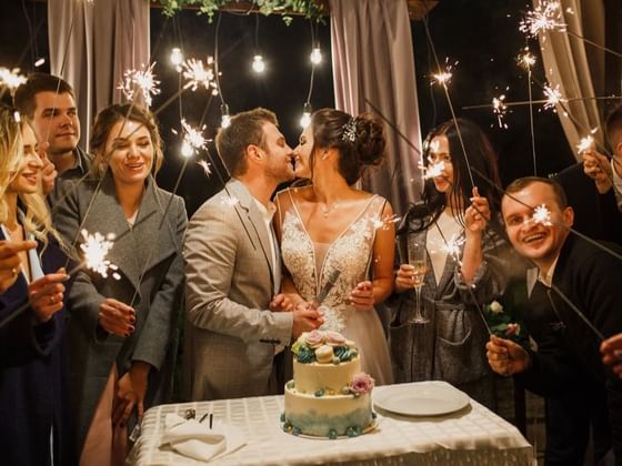 Bride & groom kissing each other while cutting cake at Hotel Clique Calgary Airport