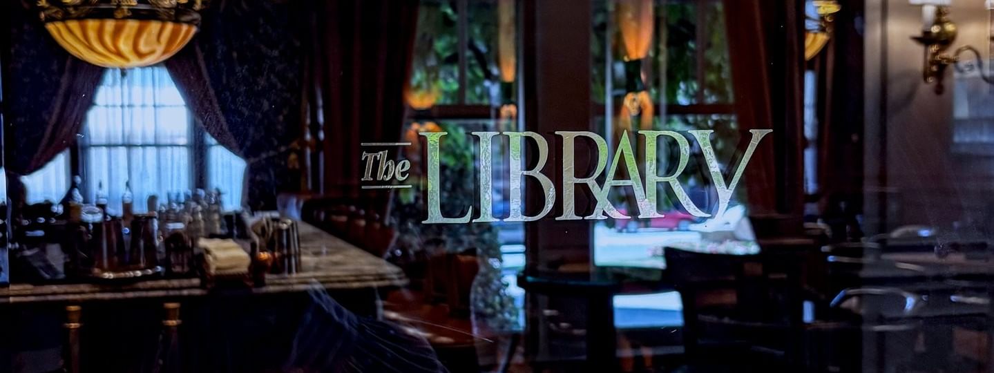 The Library with a chandelier under a dark ceiling at Warwick Melrose Dallas