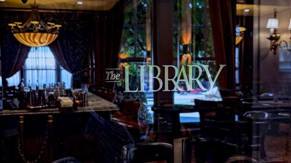 The Library with a chandelier under a dark ceiling at Warwick Melrose Dallas