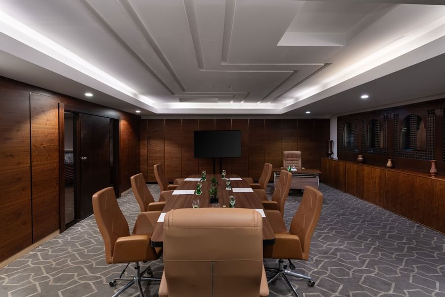 Boardroom set-up with notepads, green bottles, and carpeted floors in a meeting room at Warwick Hotel Jeddah