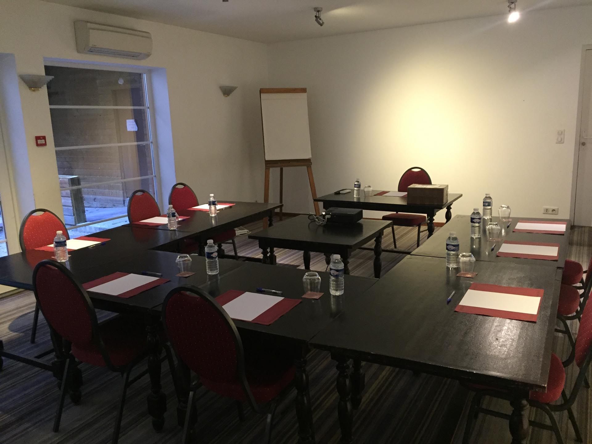 A hall arranged for a meeting with black tables and red chairs