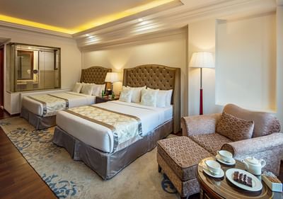 Lounge area by the beds with cushioned headboards in Classic Family Twin Room at The Indus Valley Leh, Ladakh Rooms
