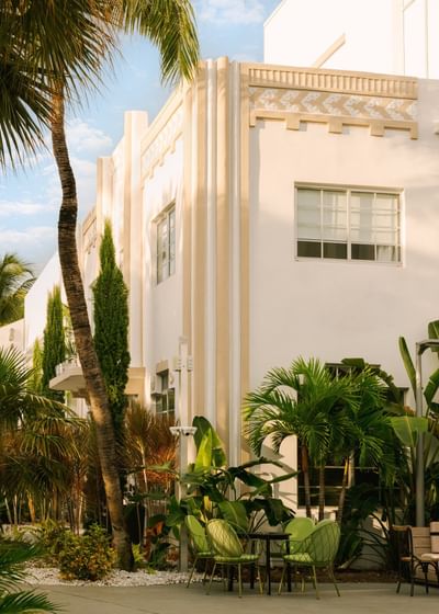 Art Deco hotels Miami, featuring a sunlit outdoor seating area and tropical palm trees at Kenmore Village Hotel South Beach