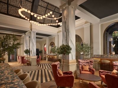 Grand lounge and bar at The Met Hotel Leeds, England, with marble columns, terracotta seating, and a black and white floor