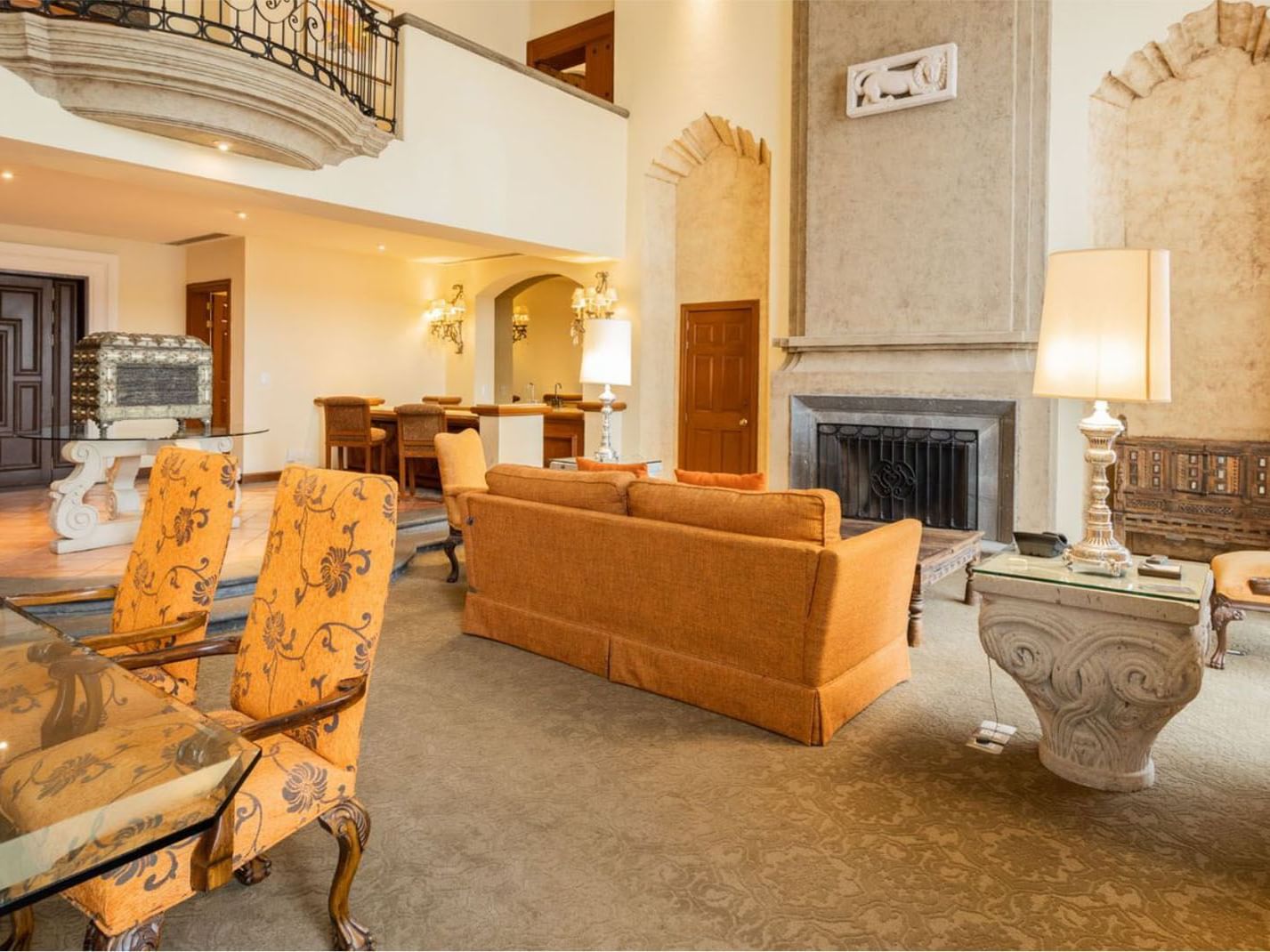 King Presidential Suite living room featuring orange sofas, a classic fireplace and a large balcony at Quinta Real Monterrey