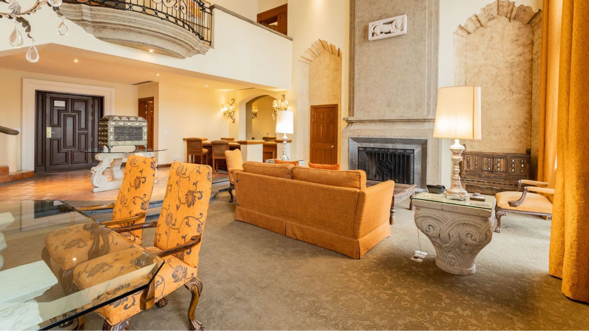 King Presidential Suite living room featuring orange sofas, a classic fireplace and a large balcony at Quinta Real Monterrey