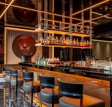 Moderne Bar mit geschwungener Theke, Barhockern und goldener Beleuchtung in The Main Bar im Titanic Gendarmenmarkt Berlin