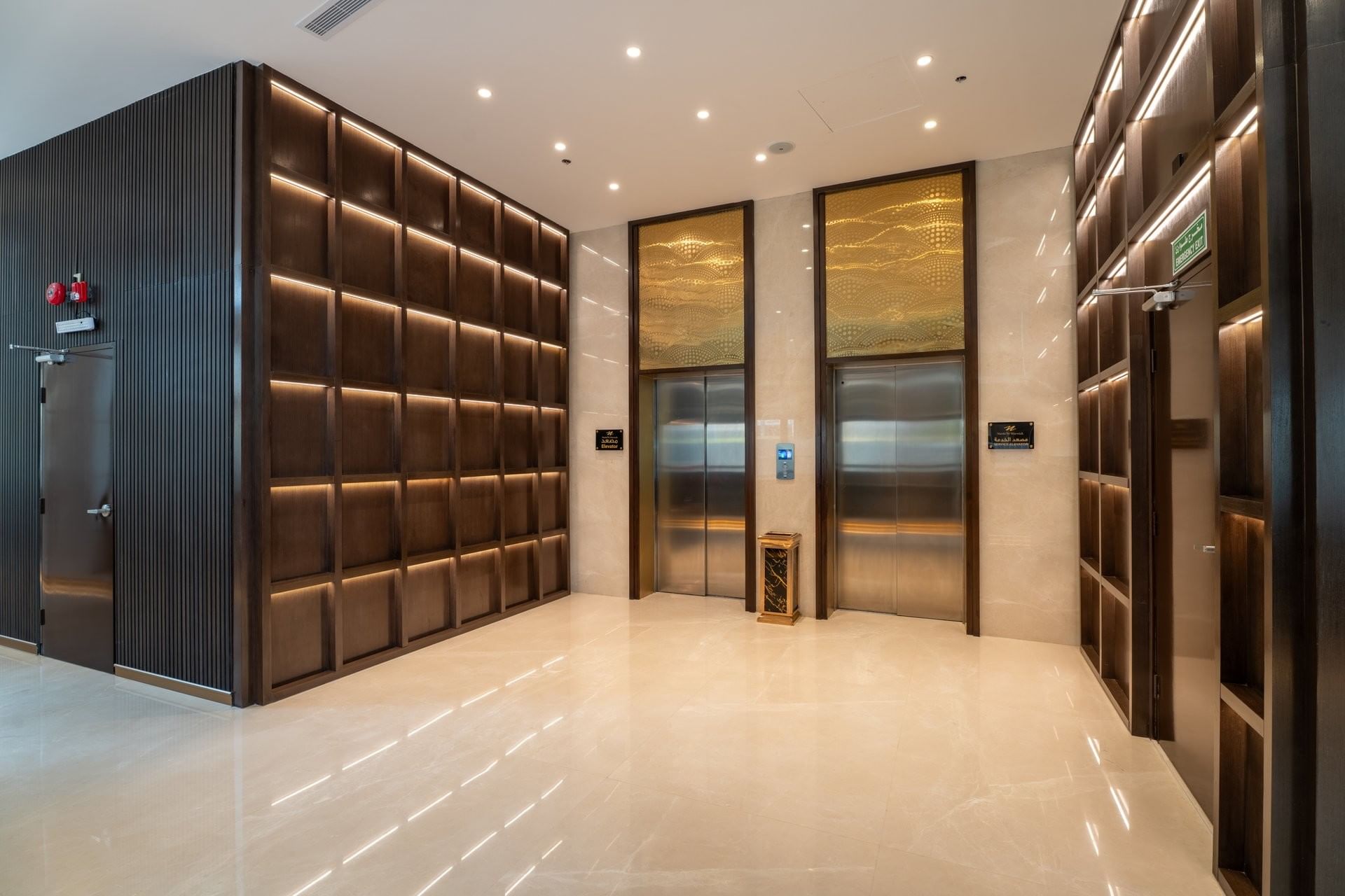 Modern elevator landing with grid wood wall panels beside two silver lift doors inside the Naviti by Warwick Jeddah hotel