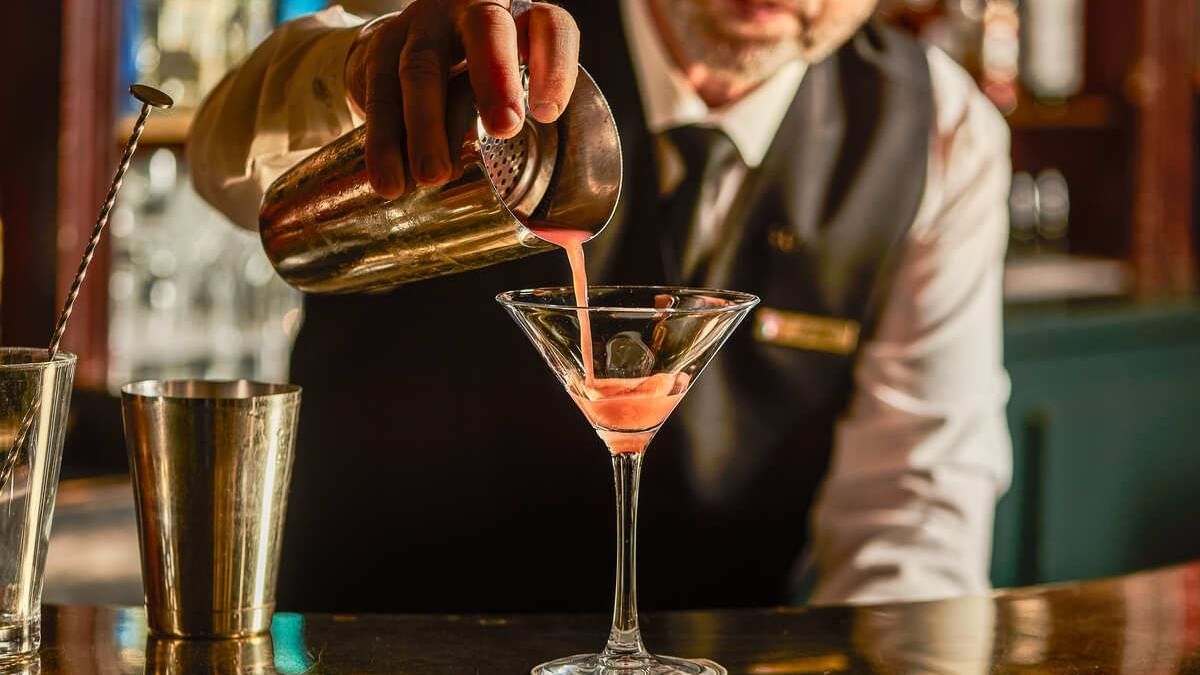 A bartender pours a pink cocktail from a shaker into a martini glass at Westminster Warwick Paris