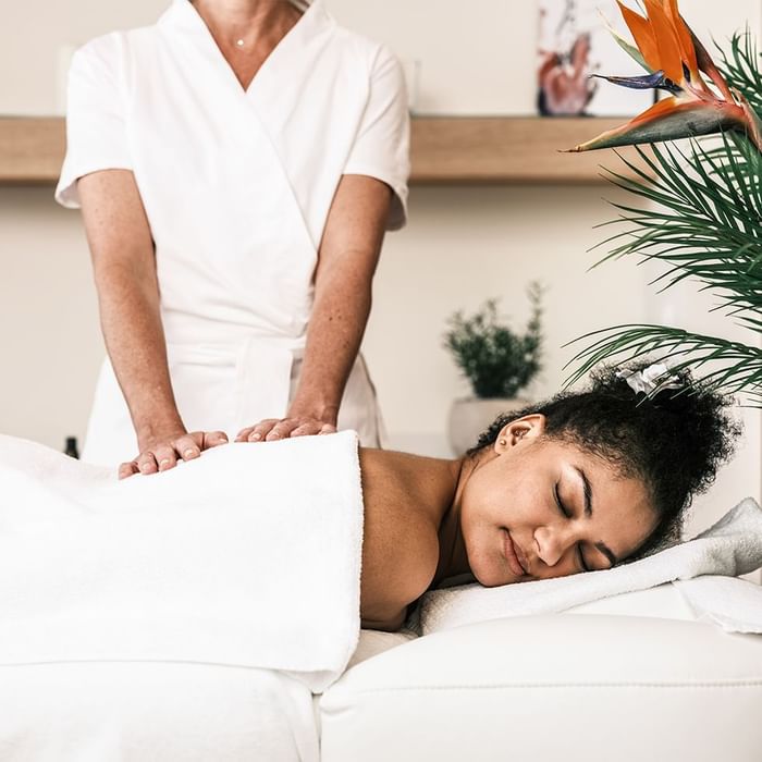 Frau erhält eine Massage auf einer weißen Liege von einer Therapeutin in einem weißen Kittel.