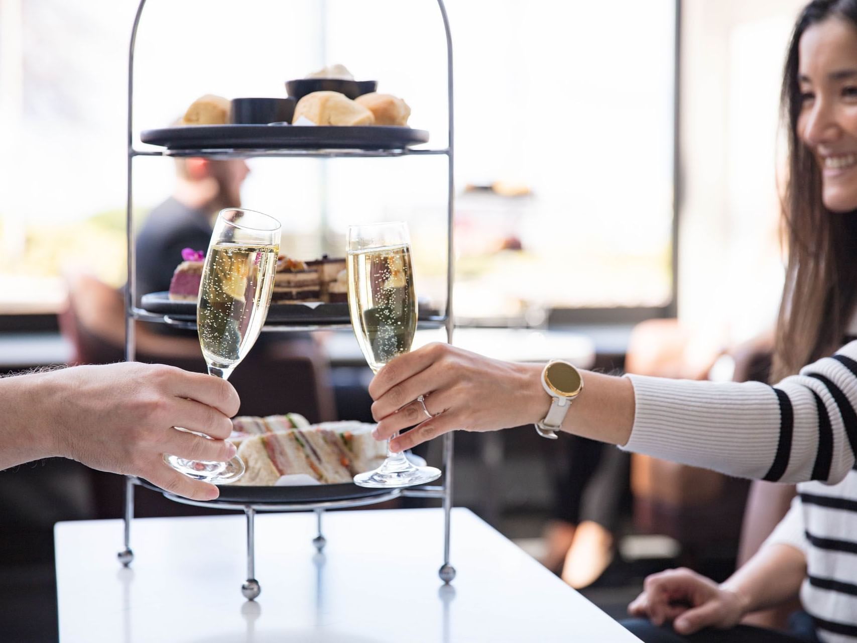 Couple raising their glasses filled with champagne at afternoon tea in Hotel Grand Chancellor Hobart