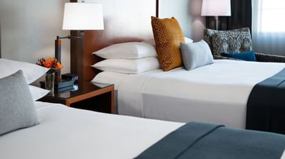 Bedding and cozy pillows on the beds with a nightstand and lamp in Queen Balcony ADA Accessible at Paramount Hotel Portland