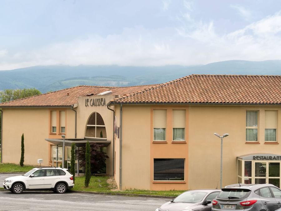 Exterior building view of Hotel Le Caussea with Mountains 