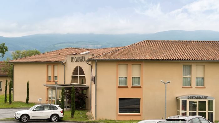Exterior building view of Hotel Le Caussea with Mountains 