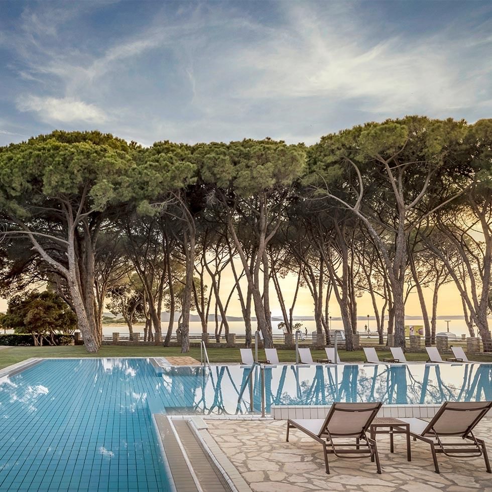 Schwimmbecken mit Liegen und Bäumen bei Sonnenuntergang, Long stay special.