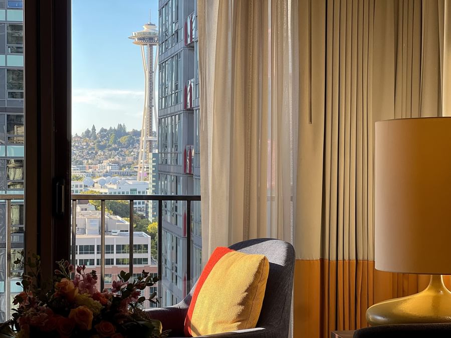 Comfortable chair with a yellow pillow near a window with curtains at Warwick Seattle.