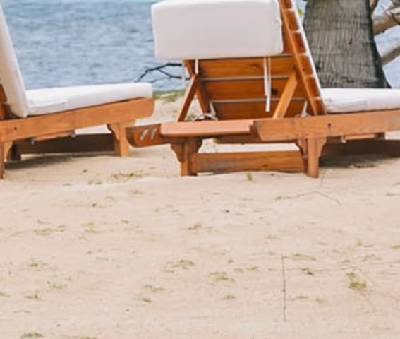 Close-up of wooden lounge chairs with white cushions at Barefoot Cay Resort & Marina