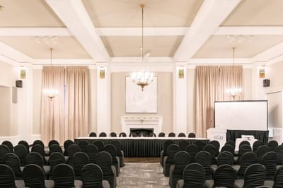 Large conference room setup with rows of black chairs and a screen at Rodd Charlottetown Hotel in Charlottetown, PEI