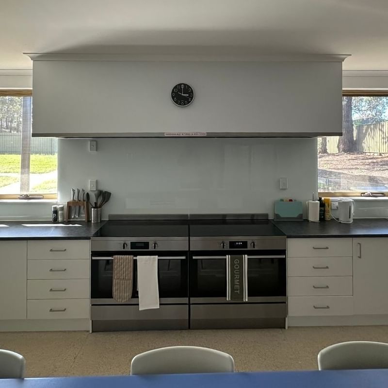 Modern kitchen with white cabinets, double ovens, and large windows at La Trobe University - Orde House.