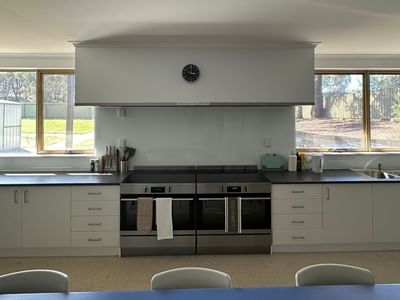 Modern kitchen with white cabinets, double ovens, and large windows at La Trobe University - Orde House.