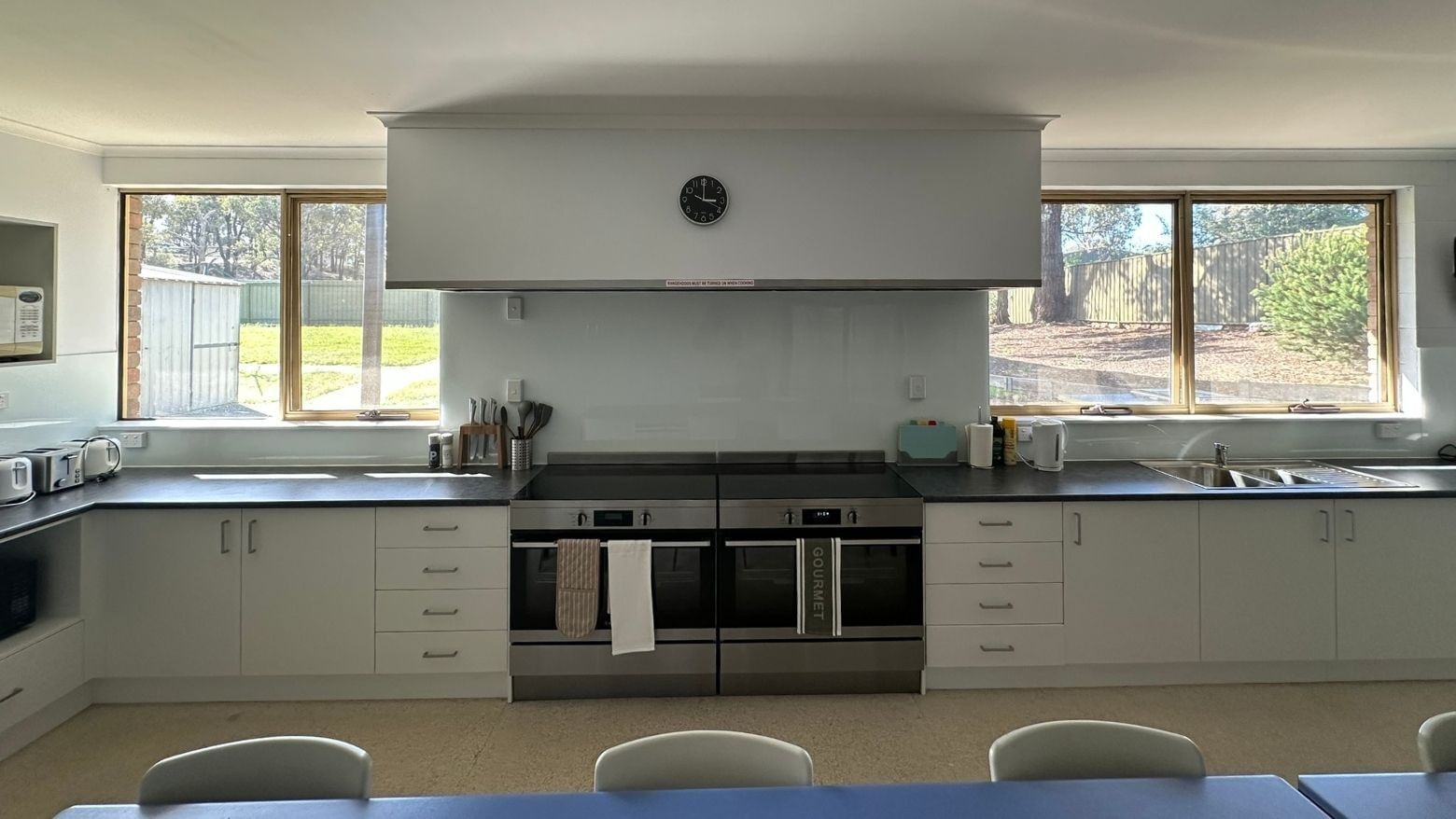 Modern kitchen with white cabinets, double ovens, and large windows at La Trobe University - Orde House.