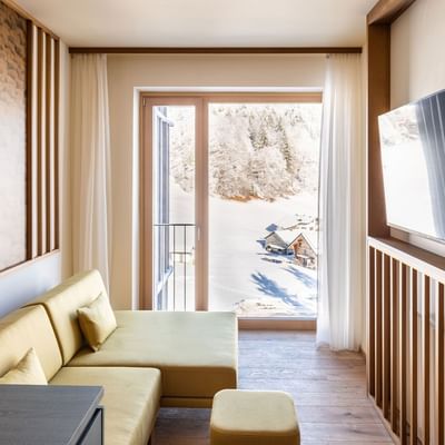 Golm Summit Suite interior with a couch, mounted TV, and a balcony at Falkensteiner Hotel Montafon
