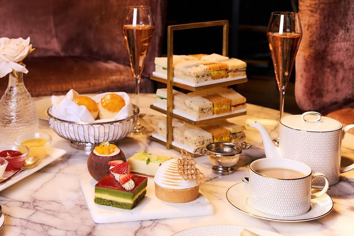 An exquisite afternoon tea spread with pastries, sandwiches, scones, and champagne at The Londoner Hotel