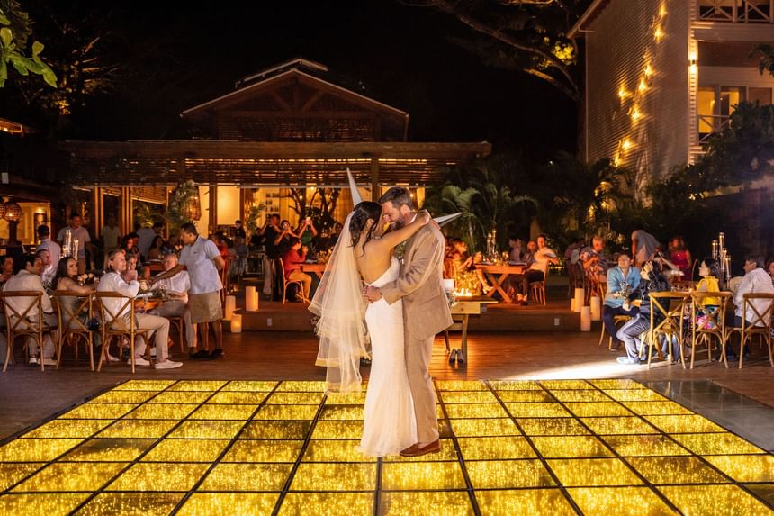 A newlywed couple shares their first dance on a sparkling dance floor, a beautiful wedding reception at Ibagari Hotel