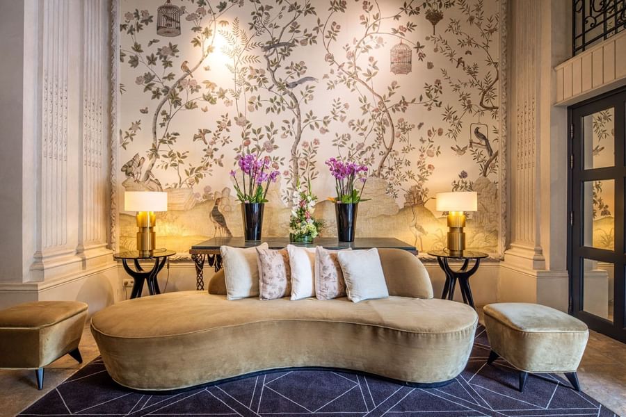 Gold curved sofa before a floral mural and purple orchids in lobby at Hotel Barsey by Warwick