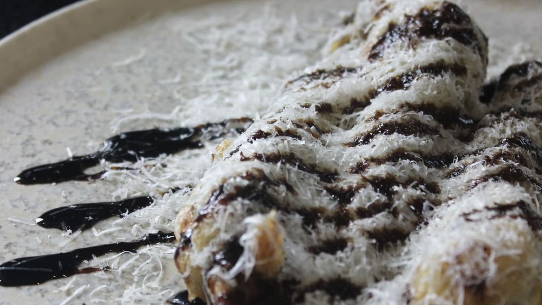 Plate with dessert covered in powdered sugar and chocolate sauce for Karinya’s Refreshed Menu.