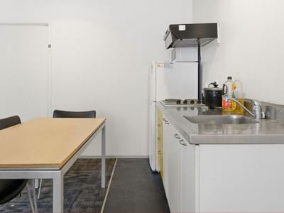 Simple kitchen with a dining table and modern white cabinets at Student Living Auckland Anzac.