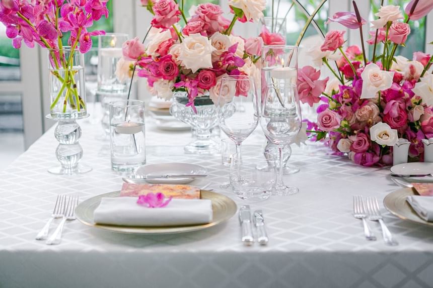 Elegant dining table set with pink floral centerpieces, gold and white place settings at Park Hyatt Saigon
