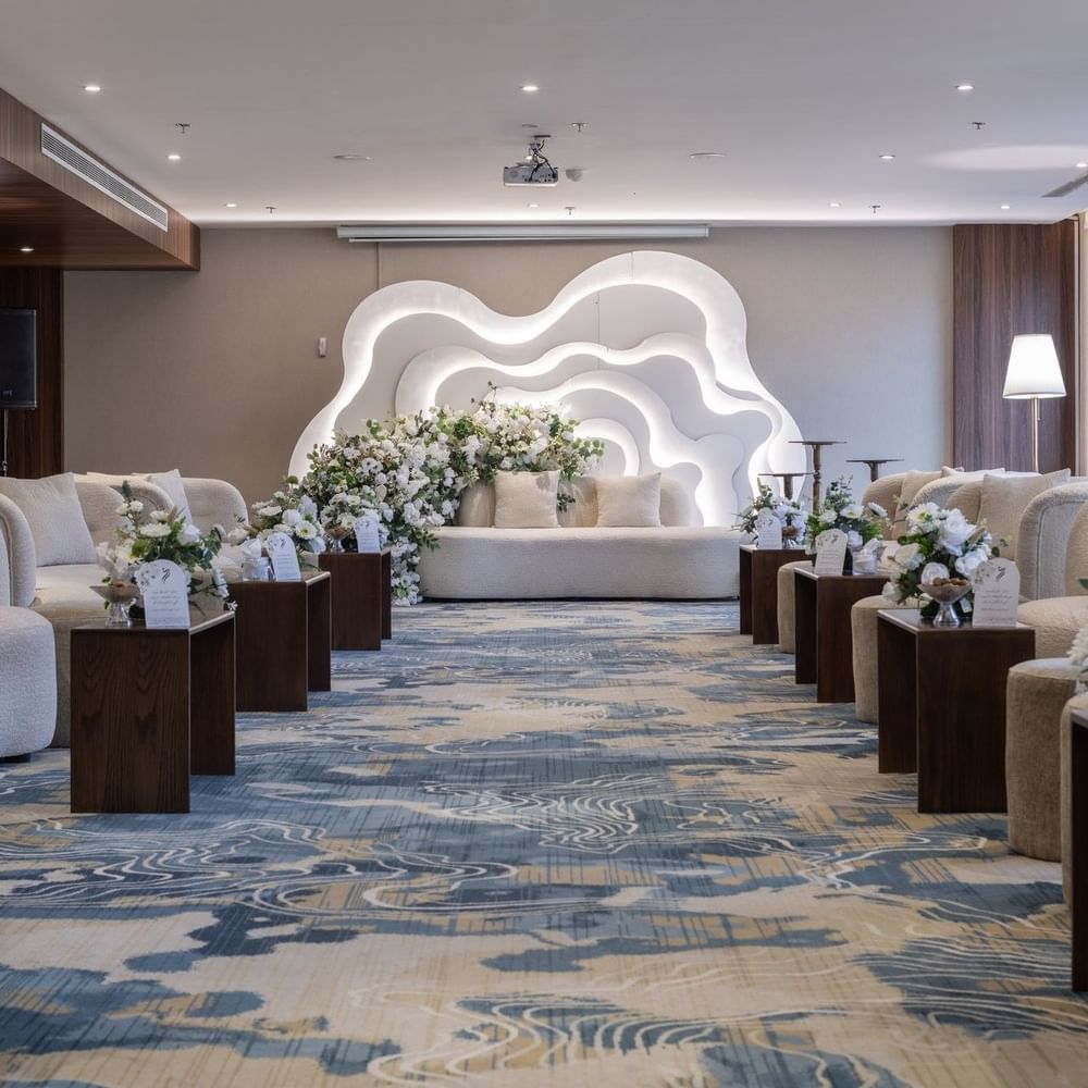 Cream sofas surrounding flower arrangements on a blue rug under bright lights in Amarige Hall at Warwick Hotels and Resorts