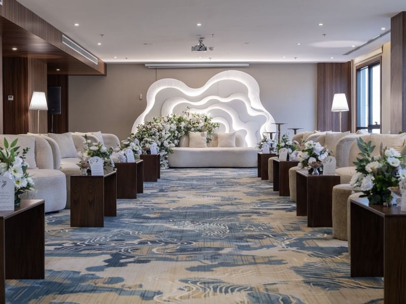 Cream sofas surrounding flower arrangements on a blue rug under bright lights in Amarige Hall at Warwick Hotels and Resorts