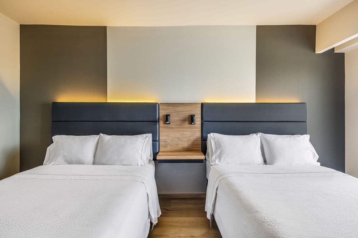 Habitación cómoda con dos camas, cabeceras oscuras y estante de madera en Fiesta Inn