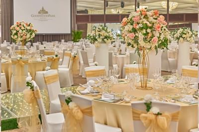 A lavishly decorated wedding ballroom at Goodwood Park Hotel with floral centerpieces and gold-draped chairs