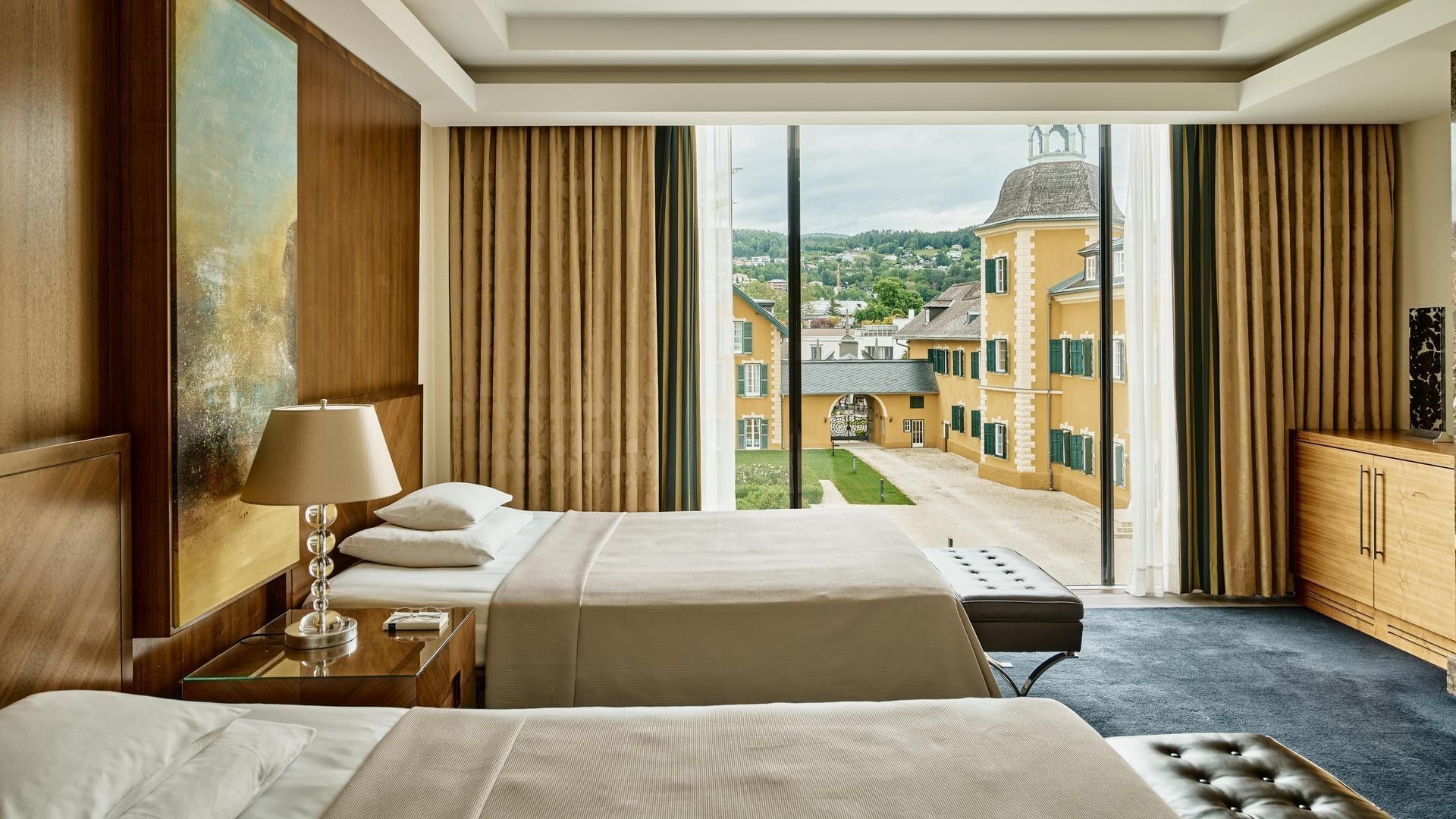 Hotelzimmer mit zwei Betten, großem Fenster, Gemälde und Aussicht auf ein Gebäude.