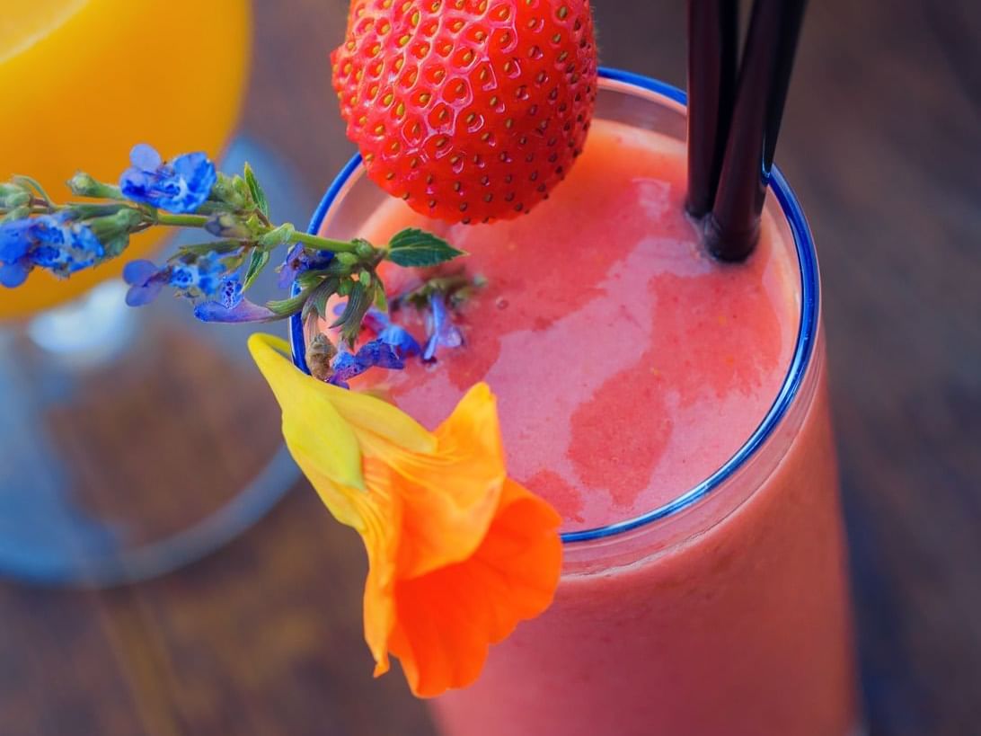 Strawberry smoothie adorned with purple and orange flowers