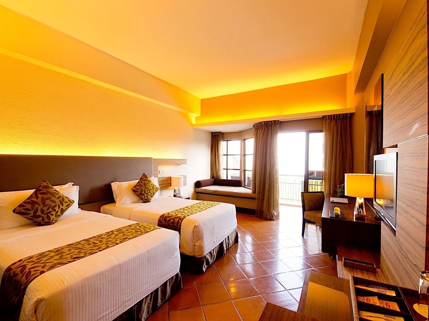 The Deluxe Garden Room with two beds, a desk, a chair, a flat-screen tv and a garden view at the Thistle Port Dickson Resort